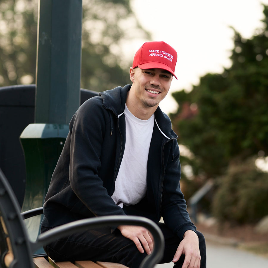 Man wearing Make Commies Afraid Again hat outdoors.