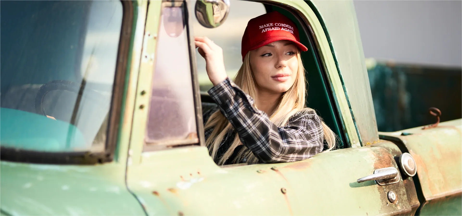 Woman in classic truck wearing Make Commies Afraid again hat. 